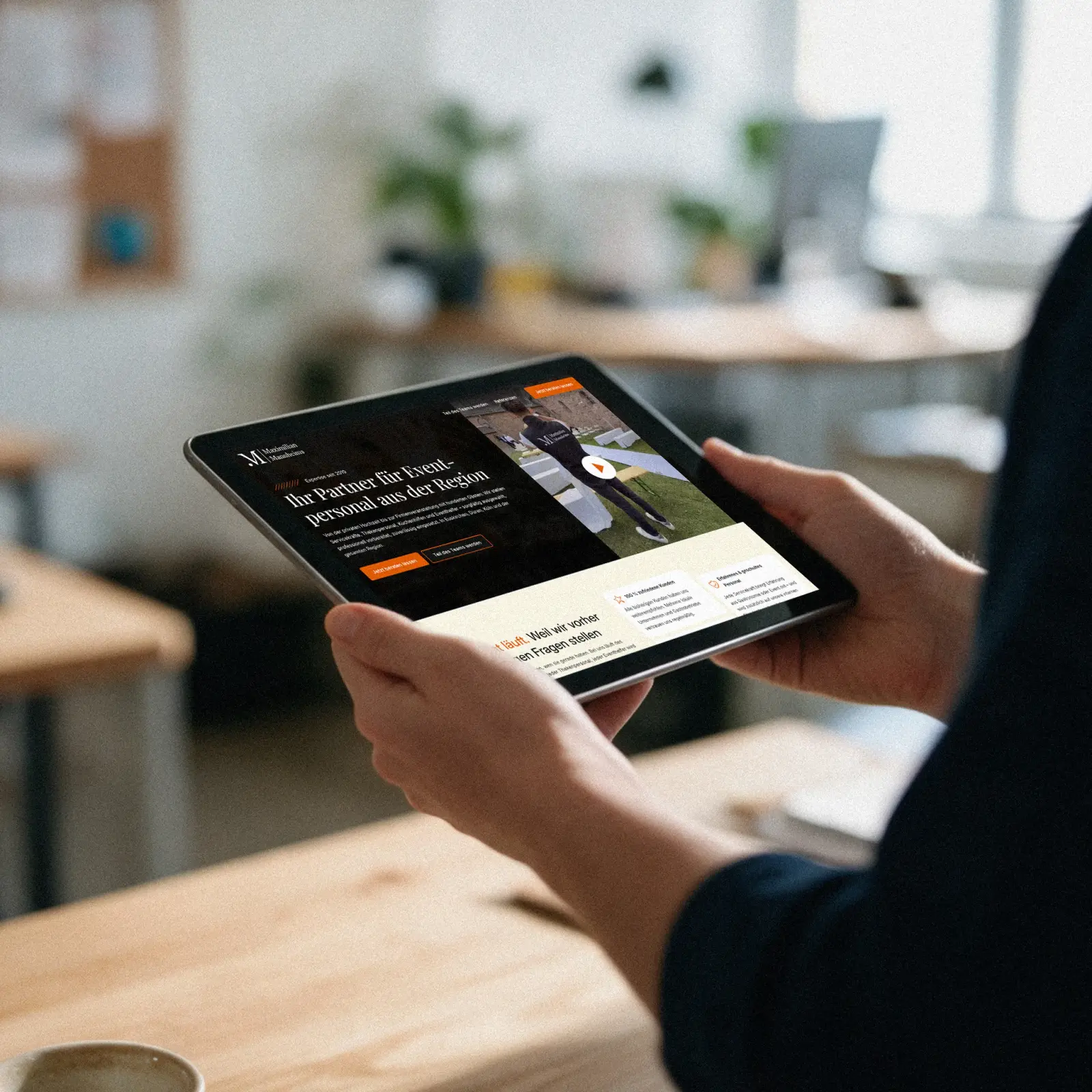 Hände halten ein Tablet mit der Website von Maximilian Mannheims in einem hellen Büro
